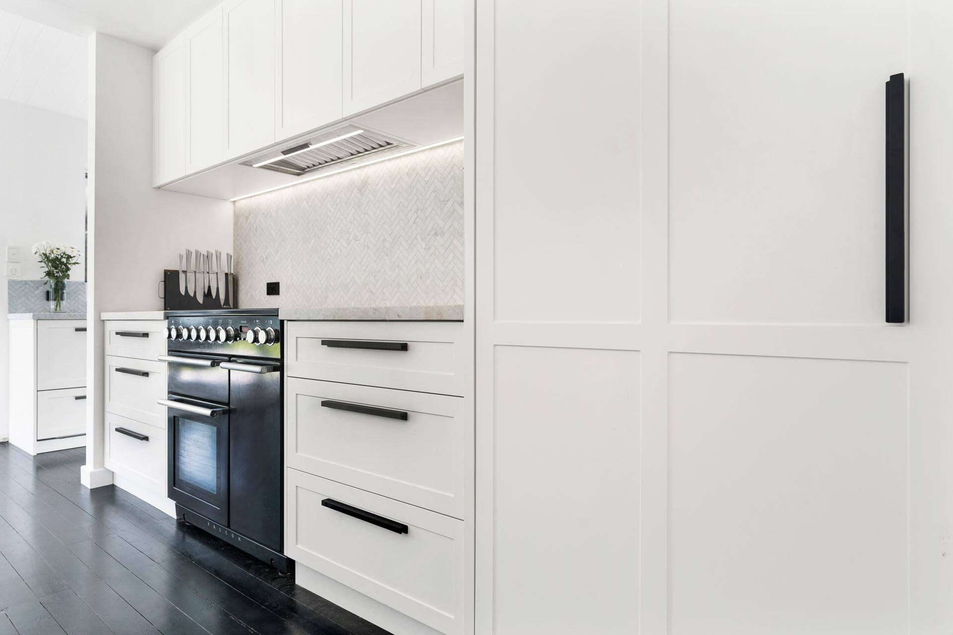 Modern shaker kitchen cabinetry with slim white profiles, integrated oven and black handles in a contemporary Perth home