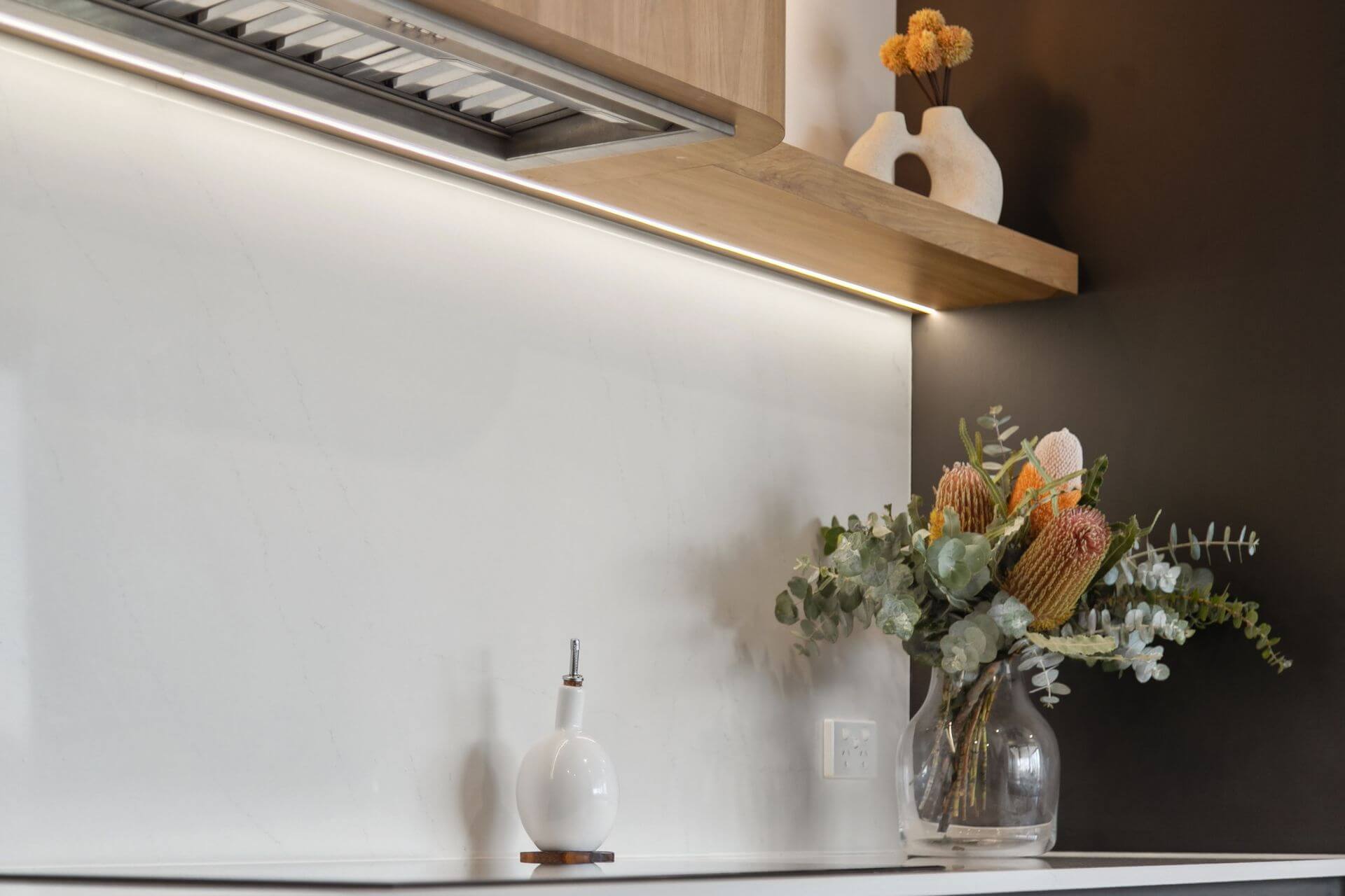 Minimalist kitchen splashback with under-cabinet lighting and decorative styling elements.